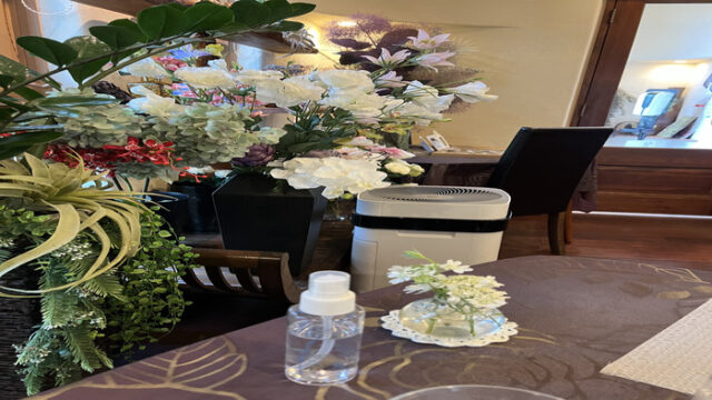 花が飾ってあり、空気清浄機が置いてある。テーブルには、小さい生け花と、消毒スプレー。